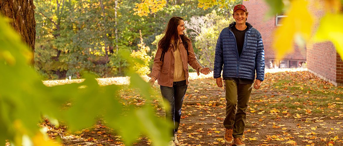 Two students walking across campus in the fall