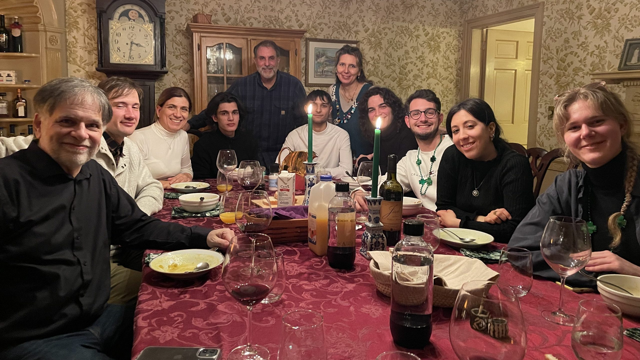 A large group of people posing for photo at a candlelit table.