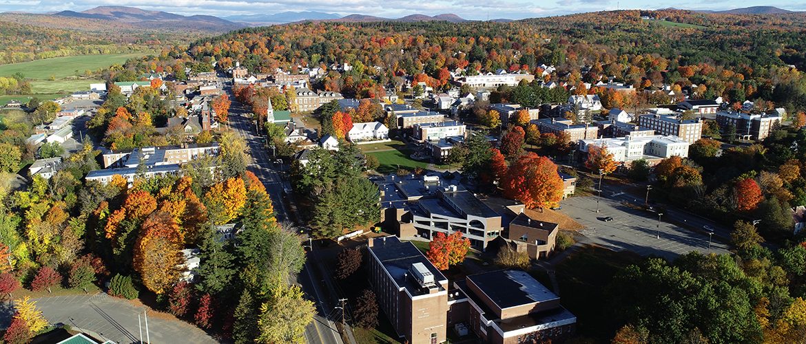 Aerial view of campus buildings, trees, and mountains